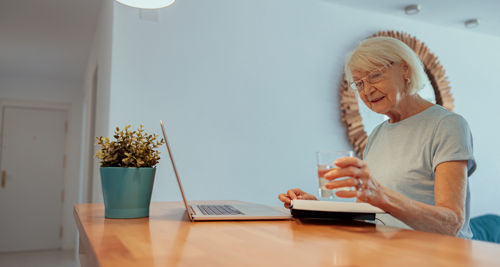 Elderly woman at laptop with glass of water