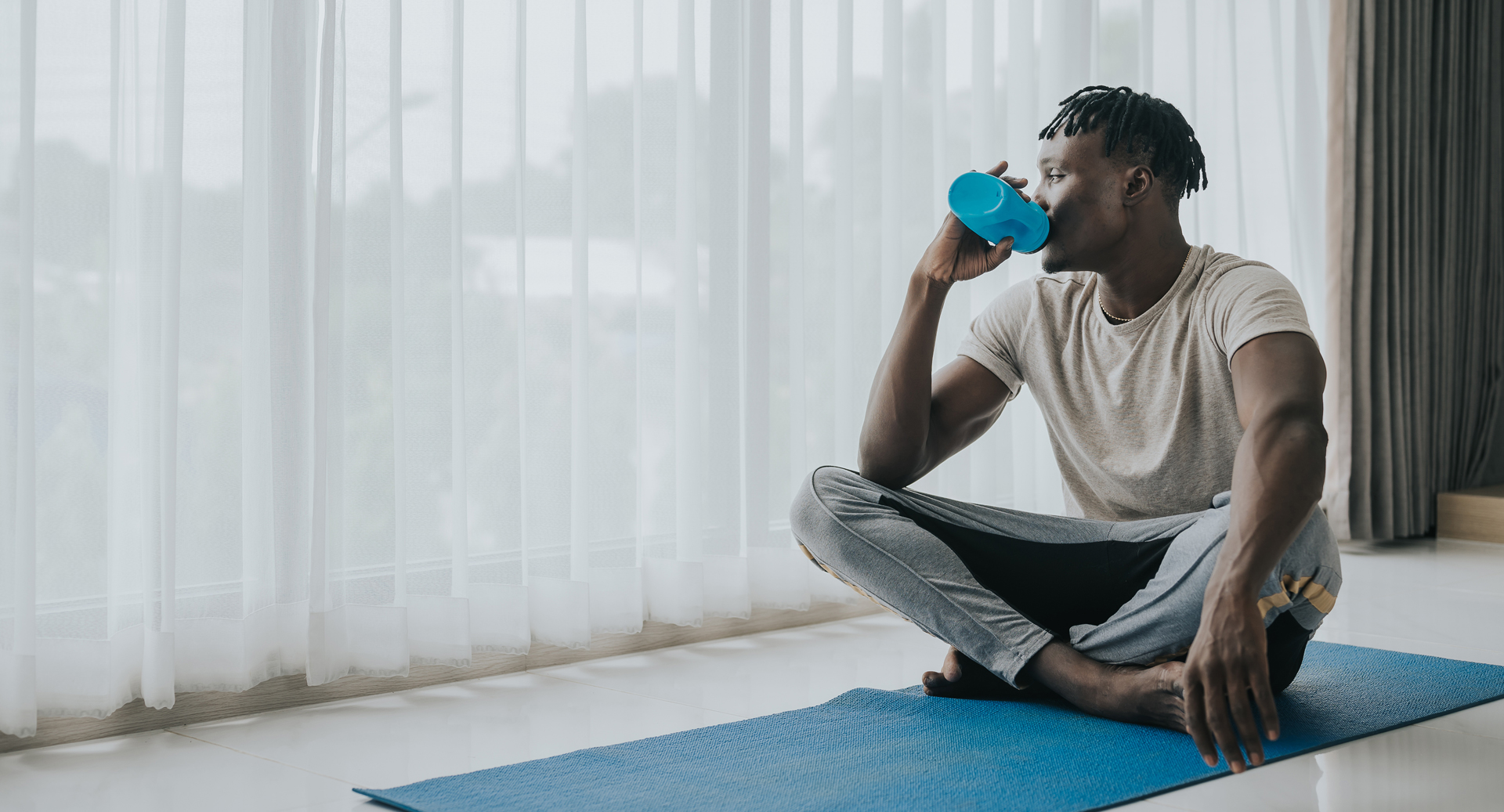 Man on yoga mat drinking water